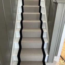 Stairs with a beige and black border carpet runner in Consett
